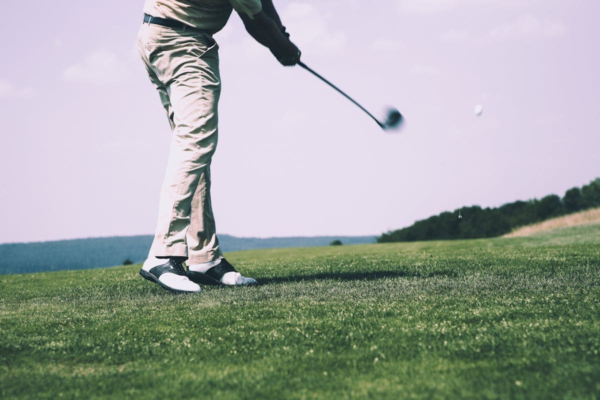 Golfer mid-swing on a green fairway