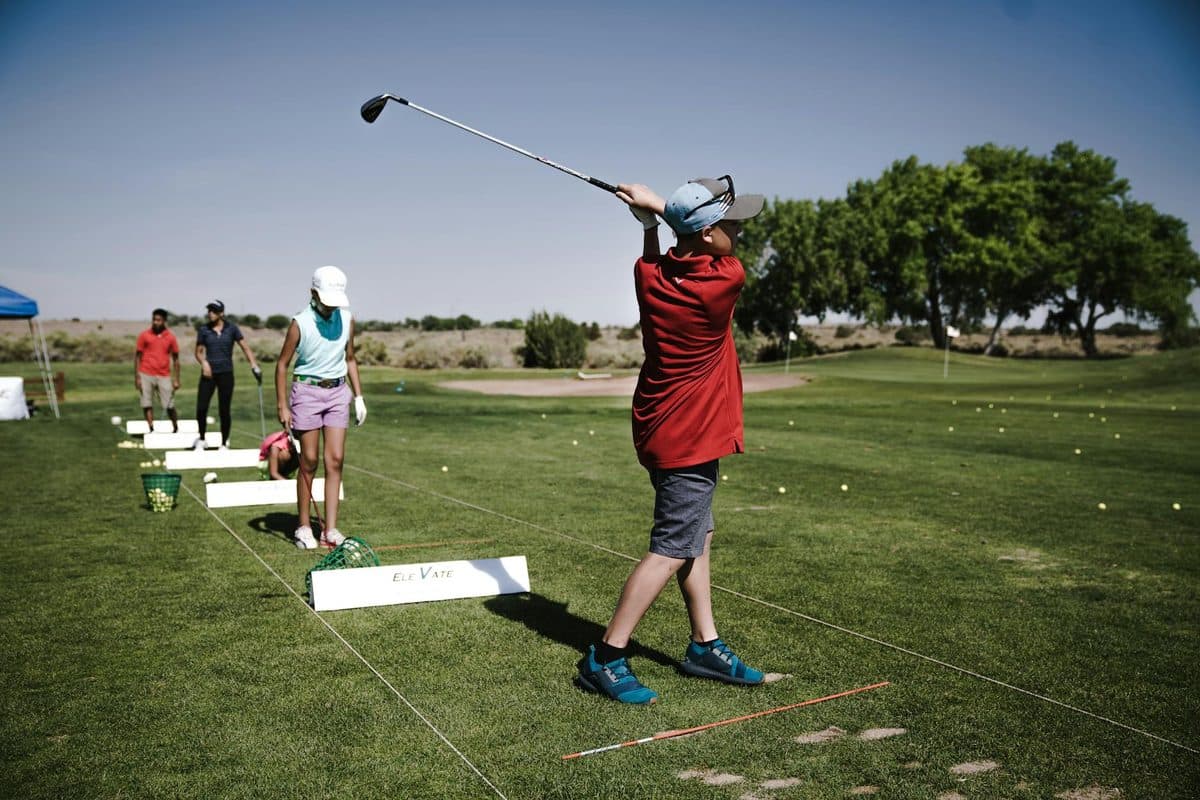 Golfer receiving a lesson at a driving range with a PGA professional