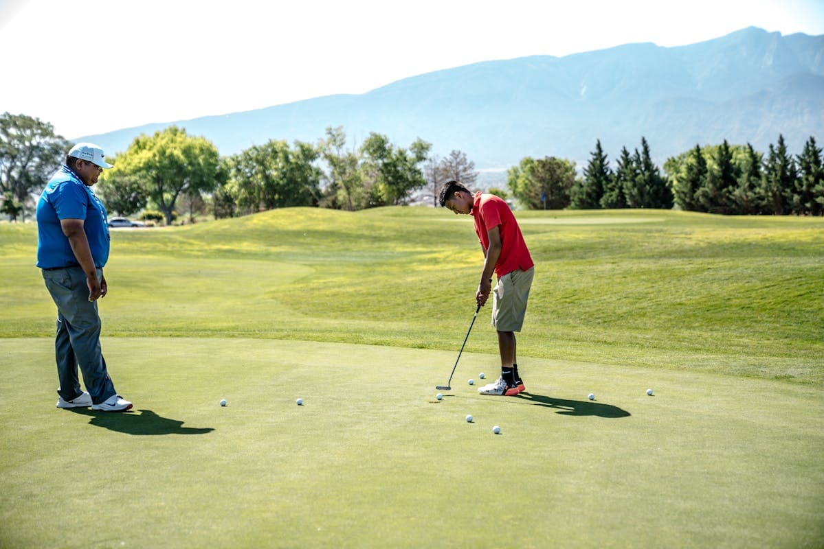Golf instructor watching a student practise putting