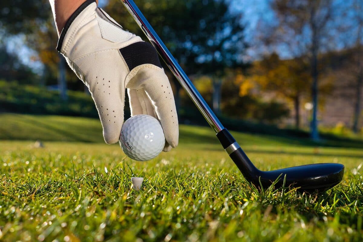Golfer placing a ball on a tee on a sunny golf course