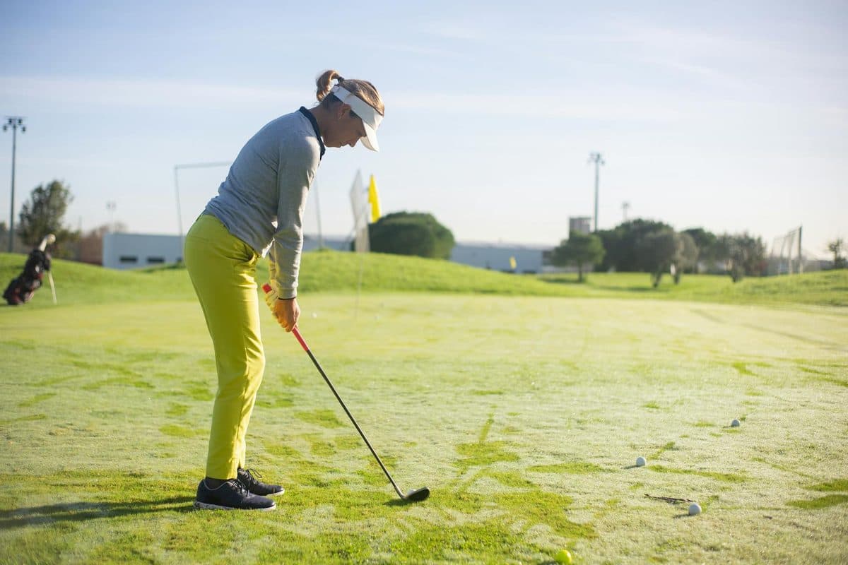 Woman golfer preparing to putt on a sunny golf course